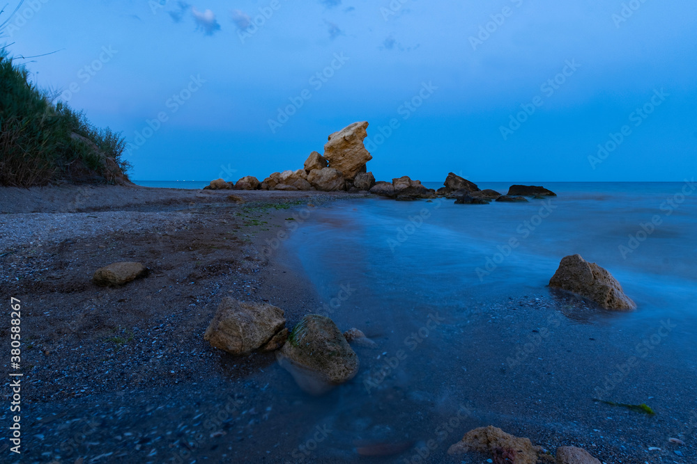 Landscape with sea, river and stones after sunset