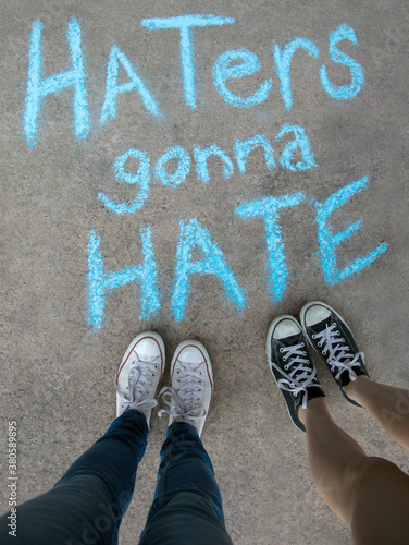 Two kids standing above chalk words that say Haters gonna Hate photo
