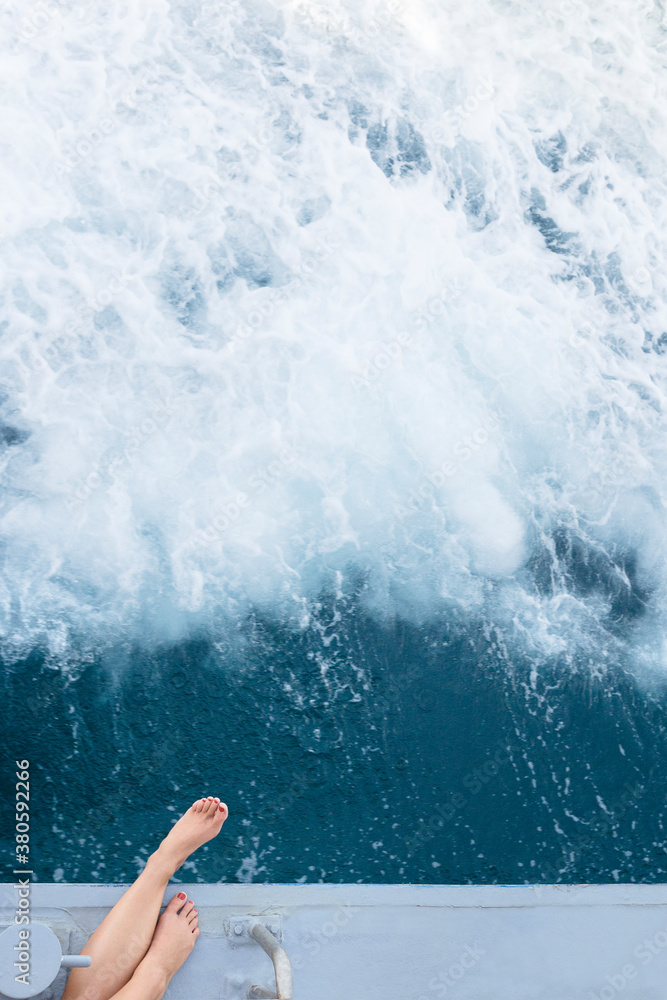 Above view of the legs of a woman sitting on a deck of the ship enjoying summer at the sea Above view of the legs of a woman sitting on a deck of the ship enjoying summer at the sea