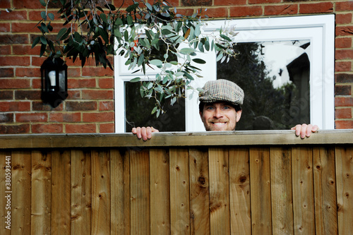 Nosy neighbor peeking over the fence, spying on his neighbours during the covid-19 lockdown photo