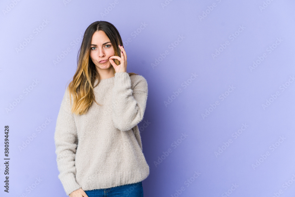 Young caucasian woman isolated on purple background with fingers on lips keeping a secret.