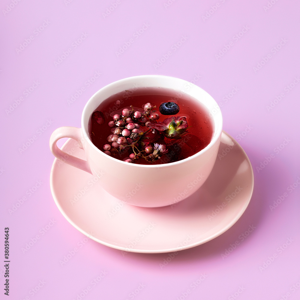 Creative layout made with tea cup filled with fall fruit, dried herbal and berries on pink background. Minimal Autumn concept. Creative layout made with tea cup filled with fall fruit, dried herbal and berries on pink background. Minimal Autumn concept.