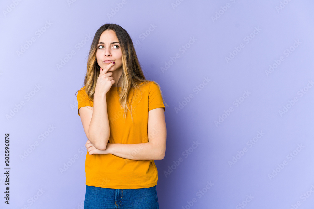 Young caucasian woman isolated on purple background thinking and looking up, being reflective, contemplating, having a fantasy. Young caucasian woman isolated on purple background thinking and looking up, being reflective, contemplating, having a fantasy.