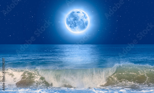 Full moon rising over empty ocean at night  power sea wave in the foreground Elements of this image furnished by NASA 