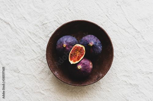 Draufsicht auf frische Feigen in einer rustikalen Schüssel auf einem beigen Leinen Tischtuch. Gesunde Ernärhung, Obstschüssel.