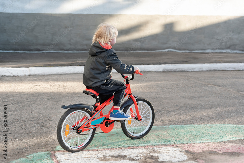 Rear view of boy riding a bicycle. Child learns to ride bike. Activity Rear view of boy riding a bicycle. Child learns to ride bike. Activity