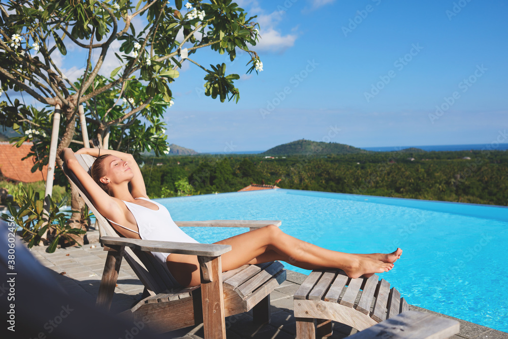 Young woman lounging on deckchair near swimming pool