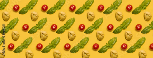 Many tortellini with basil leaf and cherry tomatoes on yellow background. Italian food pattern