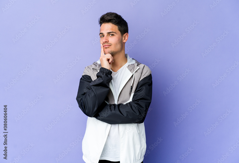 Young caucasian man isolated on purple background looking sideways with doubtful and skeptical expression.