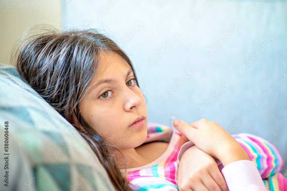 Teenage girl lying in bed checking temperature Teenage girl lying in bed checking temperature