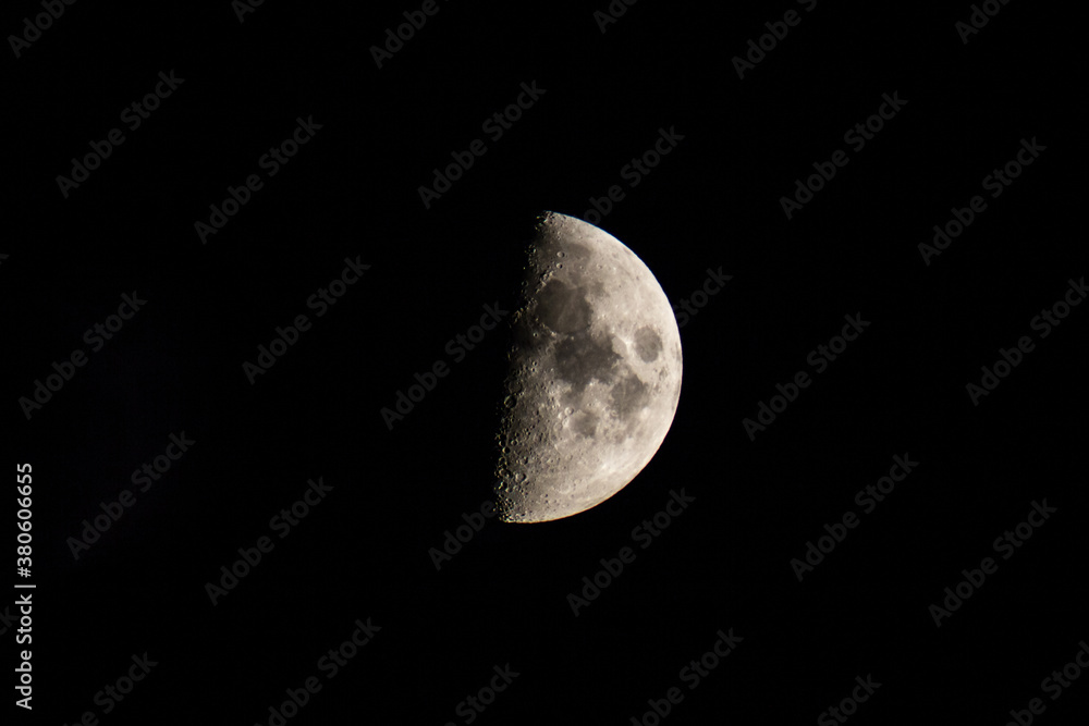 Half-lit moon against the black night sky