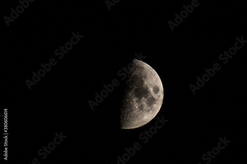 Half-lit moon against the black night sky