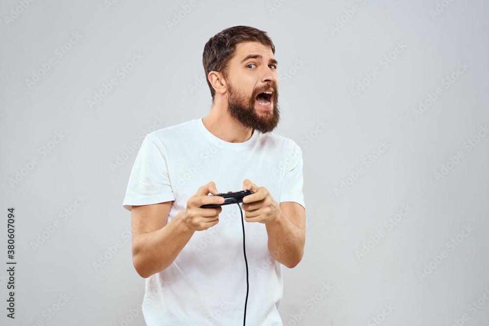 Naklejka premium A man with a gamepad in his hands playing games leisure lifestyle technology white t-shirt light background