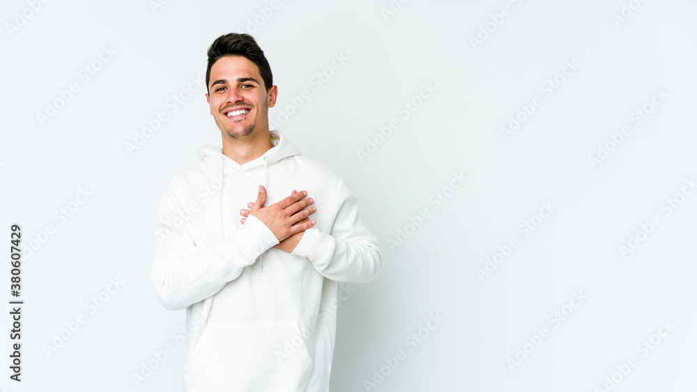Young caucasian man isolated on white background has friendly expression, pressing palm to chest. Love concept. Young caucasian man isolated on white background has friendly expression, pressing palm to chest. Love concept.