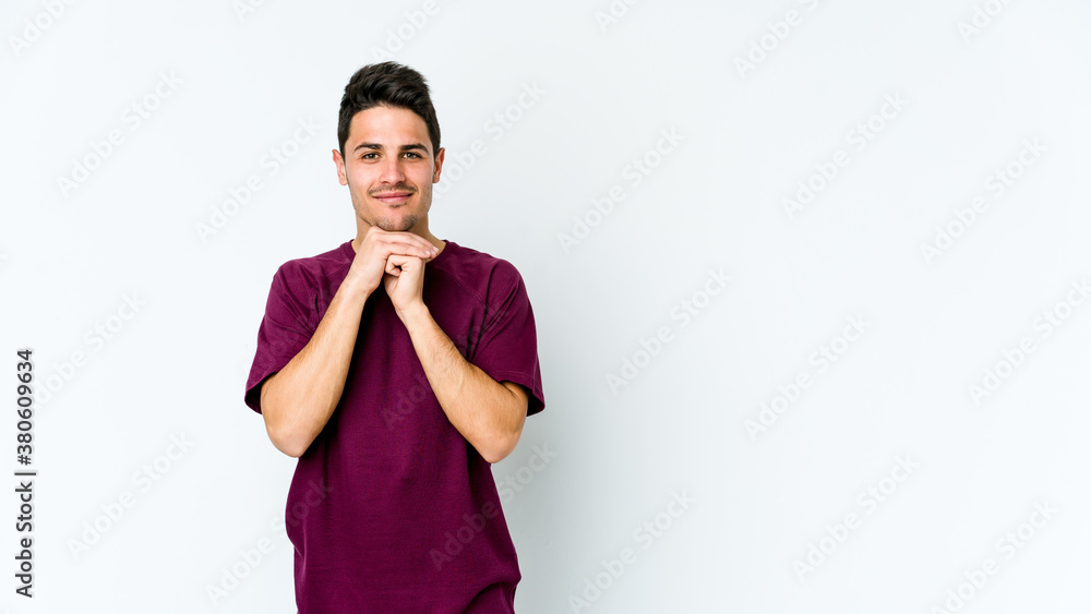 Young caucasian man isolated on white background keeps hands under chin, is looking happily aside. Young caucasian man isolated on white background keeps hands under chin, is looking happily aside.
