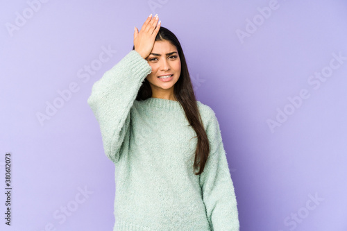 Young indian woman isolated on purple background forgetting something, slapping forehead with palm and closing eyes.