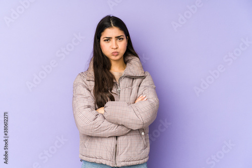 Young indian woman isolated on purple background blows cheeks, has tired expression. Facial expression concept. © Asier