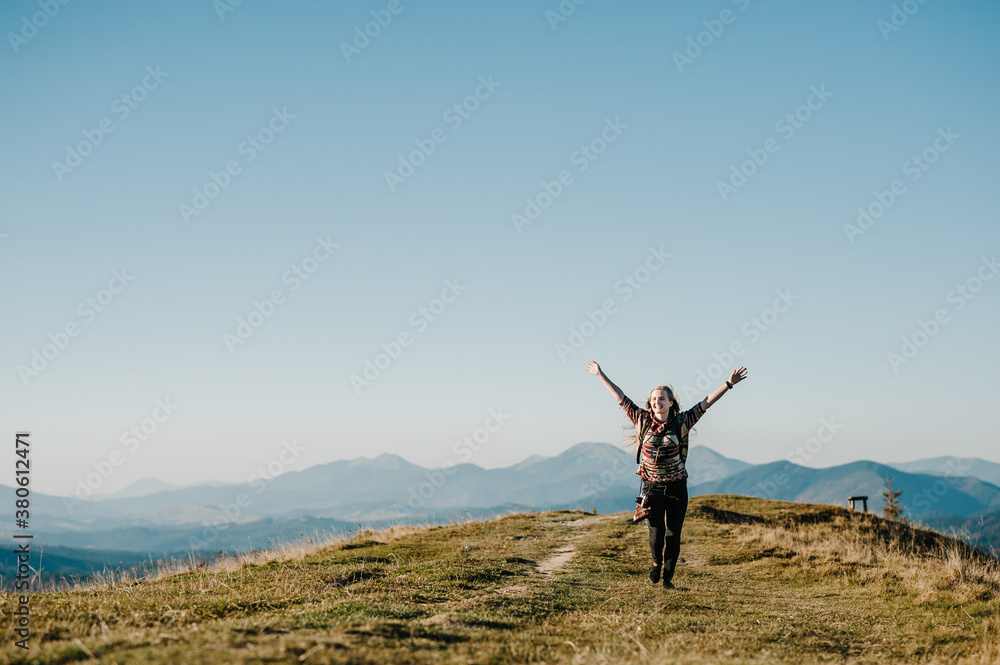 Hiker tourist in the mountains at sunset. Hipster girl with a photo camera and a backpack travels and enjoy nature. Hiker tourist in the mountains at sunset. Hipster girl with a photo camera and a backpack travels and enjoy nature.