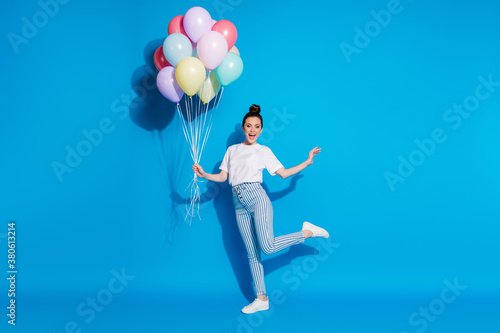 Full length body size view of nice attractive lovely pretty cheerful girl holding in hand bunch decorative air balls having fun dancing isolated on bright vivid sine vibrant blue color background