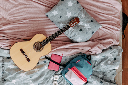 Obraz na płótnie Student's room after study. Guitar, backpack, heaphones and notebook on the bed. w salonie