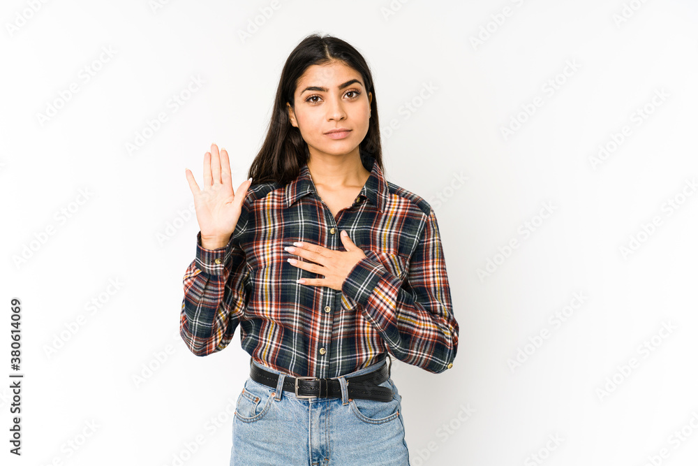 Young indian woman isolated on purple background taking an oath, putting hand on chest. Young indian woman isolated on purple background taking an oath, putting hand on chest.