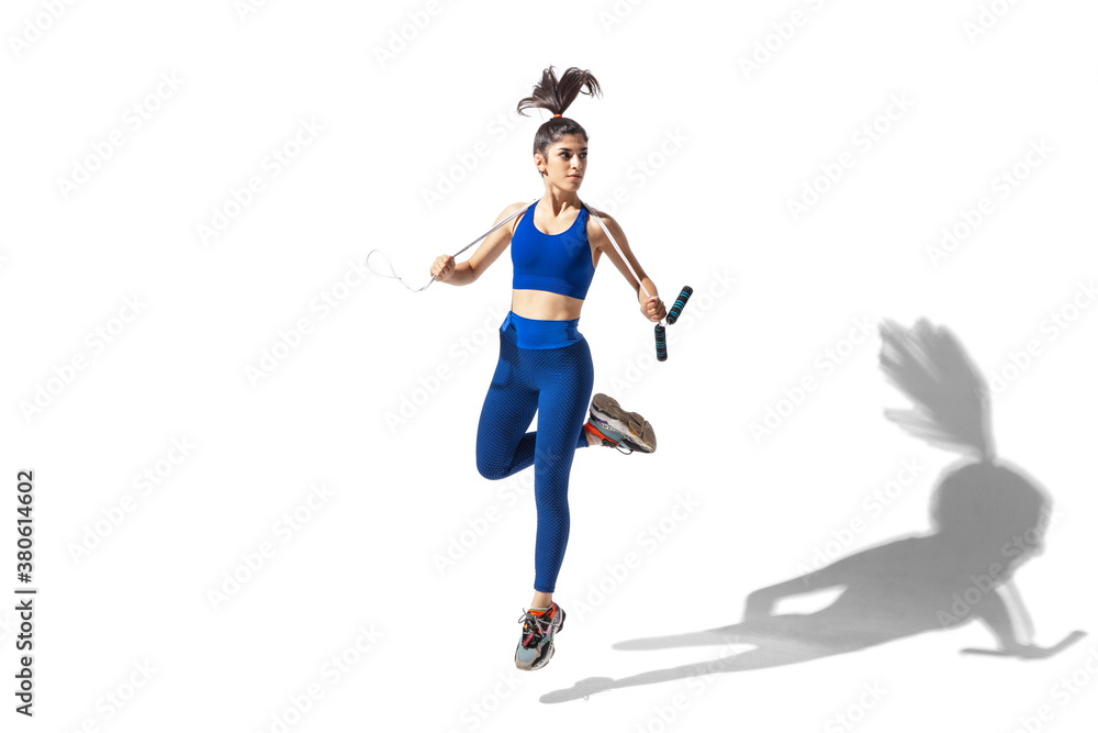 Weights. Beautiful young female athlete practicing on white studio background, portrait with shadows. Sportive fit model in motion and action. Body building, healthy lifestyle, style concept. Weights. Beautiful young female athlete practicing on white studio background, portrait with shadows. Sportive fit model in motion and action. Body building, healthy lifestyle, style concept.