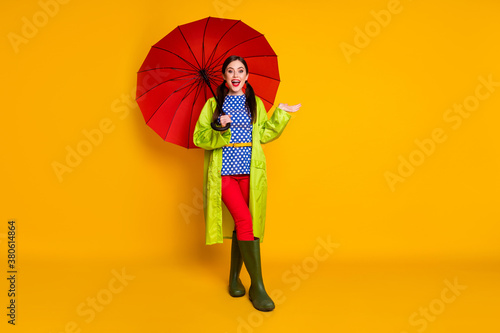 Full length photo of positive girl enjoy spring promenade hold red parasol hold hand impressed no rain drops fall wear gumshoes isolated bright shine color background
