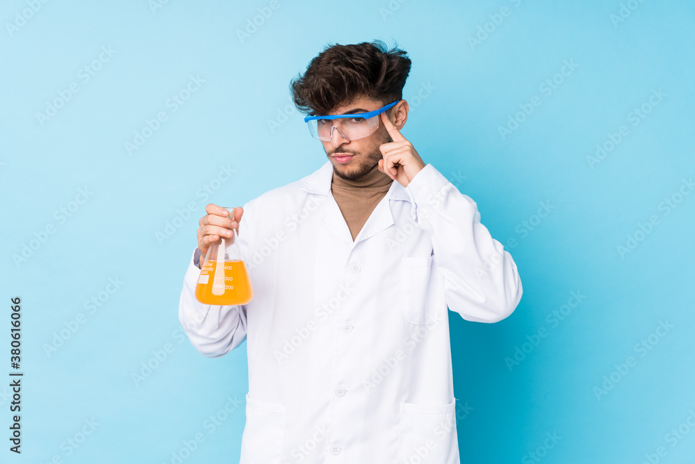 Young arab scientific man isolated pointing temple with finger, thinking, focused on a task. Young arab scientific man isolated pointing temple with finger, thinking, focused on a task.
