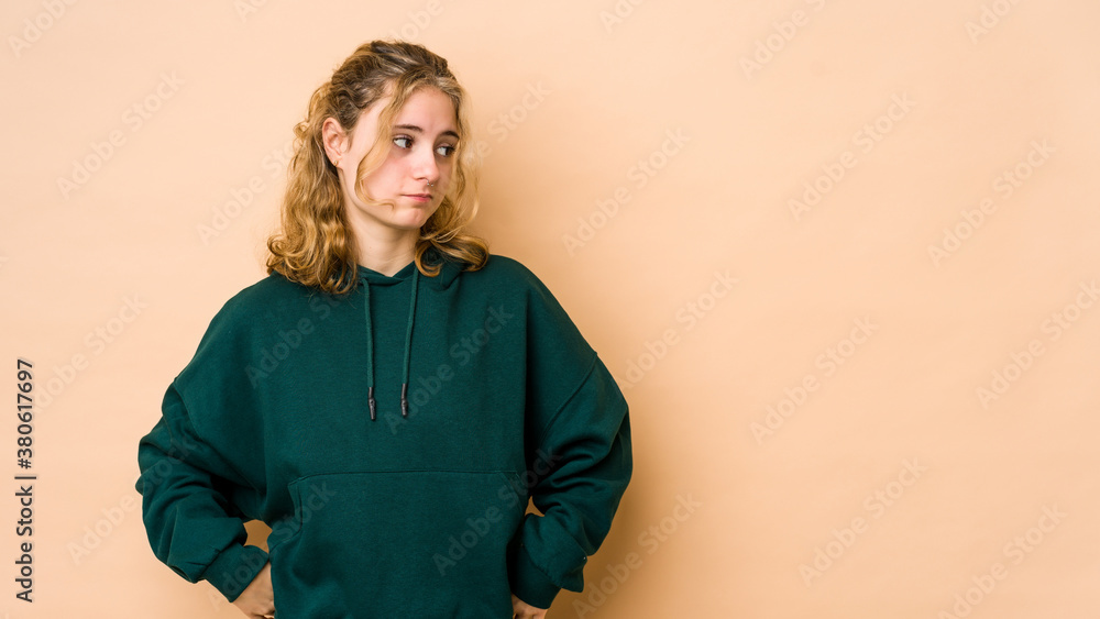 Young caucasian woman isolated on beige background confused, feels doubtful and unsure. Young caucasian woman isolated on beige background confused, feels doubtful and unsure.