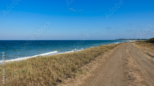 Old dirty road leading to a relaxing seascape in Europe for travel  holidays and vacation concepts. Summer vibes scene. Popular place for camping during summer vacations.