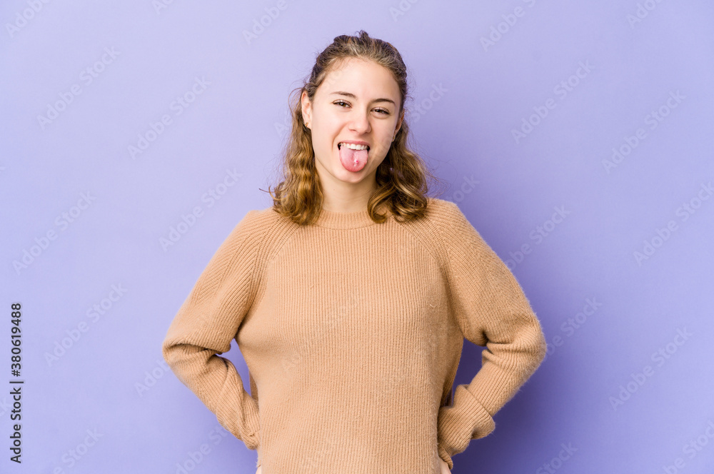 Young caucasian woman on purple background funny and friendly sticking out tongue. Young caucasian woman on purple background funny and friendly sticking out tongue.
