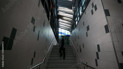 Man Going Down Stairs Wearing A Facemask In Montreal Underground Metro During The Pandemc - panning shot photo