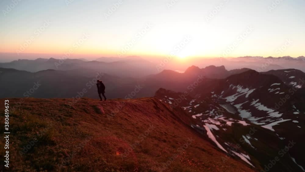 Man walking up the ridge of a mountain at sunrise in slow motion. Man walking up the ridge of a mountain at sunrise in slow motion.