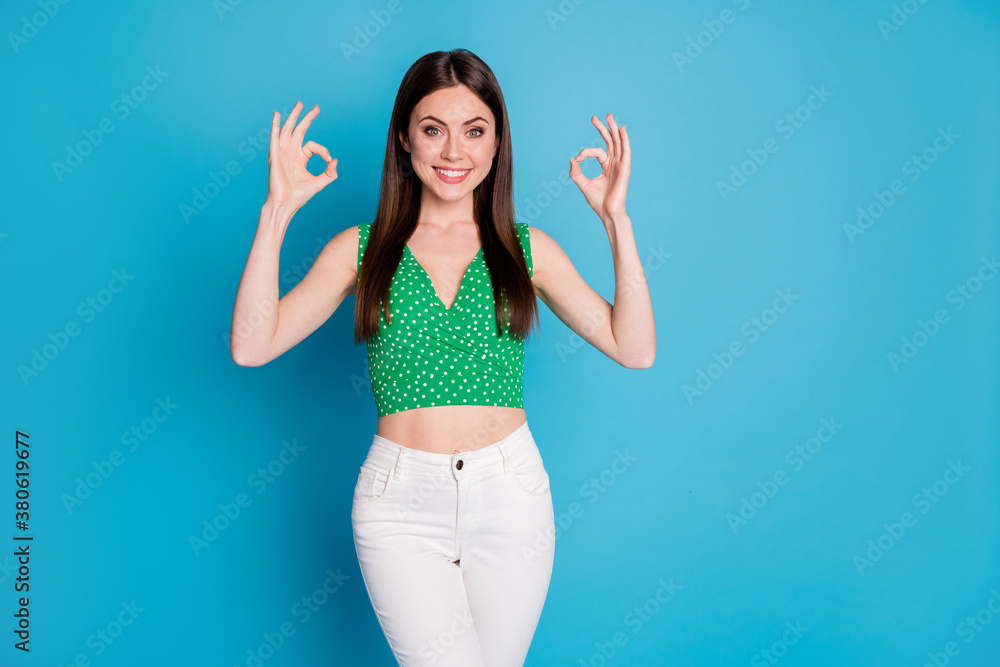Photo of attractive charming lady good mood show okey symbols arms expressing agreement wear casual green dotted cropped top naked abdomen white pants isolated blue color background Photo of attractive charming lady good mood show okey symbols arms expressing agreement wear casual green dotted cropped top naked abdomen white pants isolated blue color background