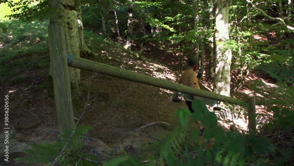 Adult man wearing shorts on summer day walks with longboard skateboard on dirt trail path in rural countryside landscape on sunny day, static lateral Adult man wearing shorts on summer day walks with longboard skateboard on dirt trail path in rural countryside landscape on sunny day, static lateral