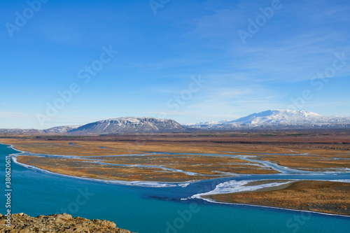 Landscape in Iceland with partly frozen rivers an two mountains in the far background.