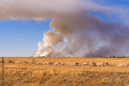 Smoke over the steppe. Fire in the steppe. Environmental disaster. Garbage in the steppe. Smoke column. Smoke screen over the plain. Dry yellow grass. Ecological problem. Environmental pollution