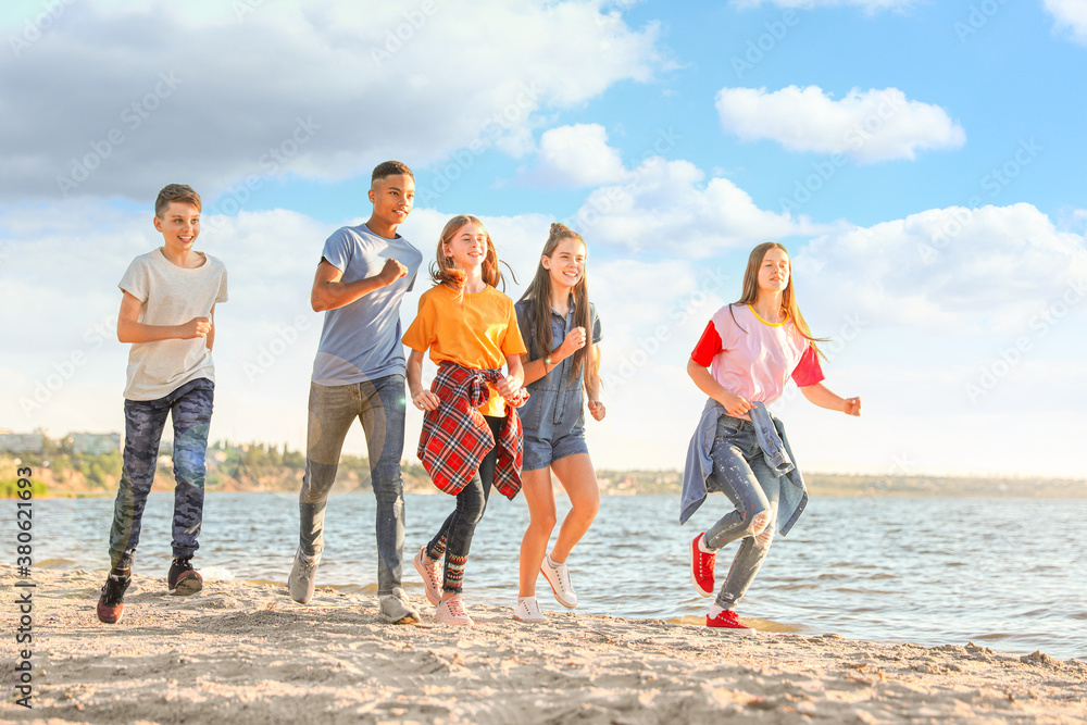 School holidays. Group of happy children running on beach