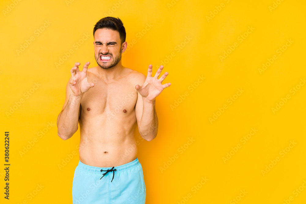 Young caucasian man with swimsuit isolated on yellow background Young caucasian man with trshowing claws imitating a cat, aggressive gesture. Young caucasian man with swimsuit isolated on yellow background Young caucasian man with trshowing claws imitating a cat, aggressive gesture.