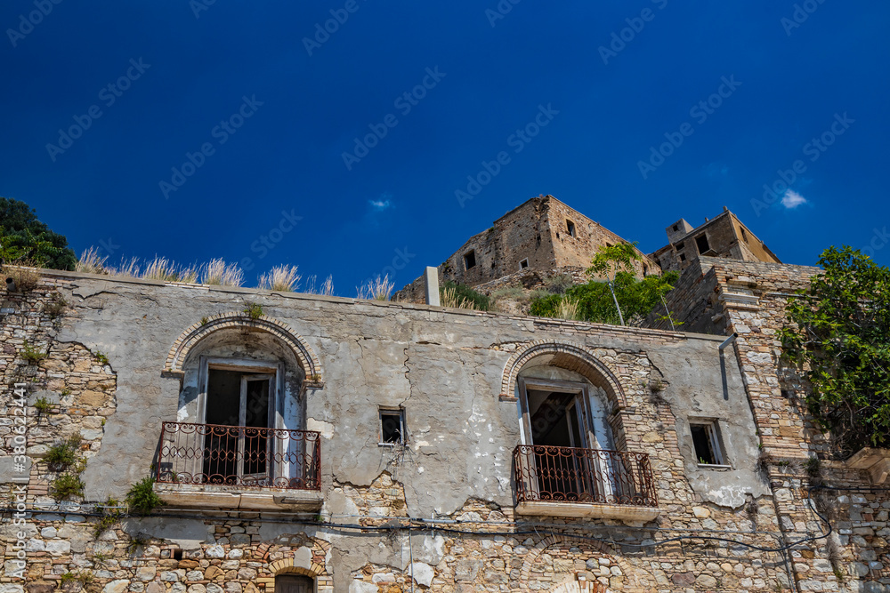 Craco, Matera, Basilicata, Italy. The ghost town destroyed and abandoned following a landslide. The collapsed houses and the remains invaded by vegetation. The broken windows with the rusty railings.