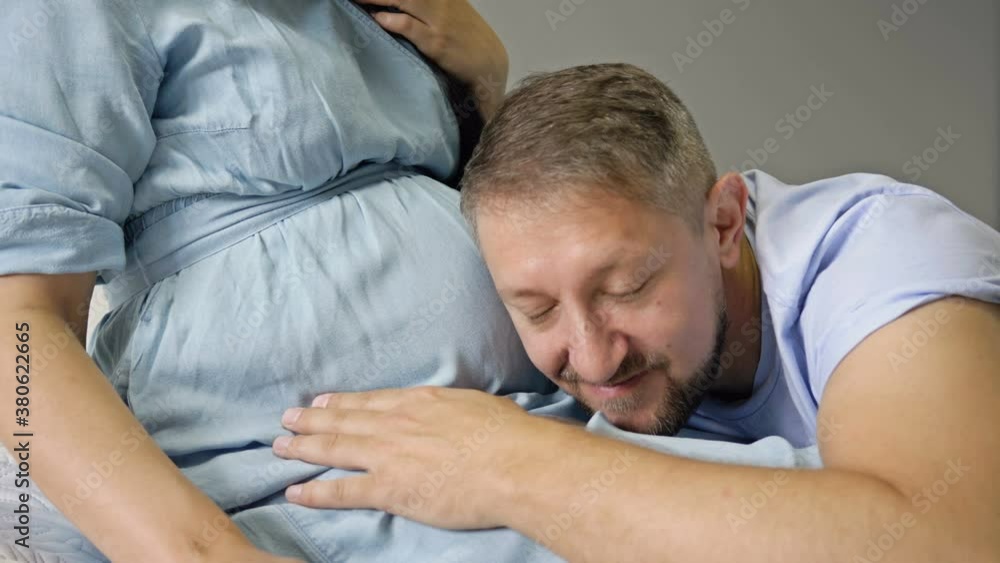 Happy man stroking and kissing the belly of his pregnant wife. Waiting for the birth of a child. Happy man stroking and kissing the belly of his pregnant wife. Waiting for the birth of a child.