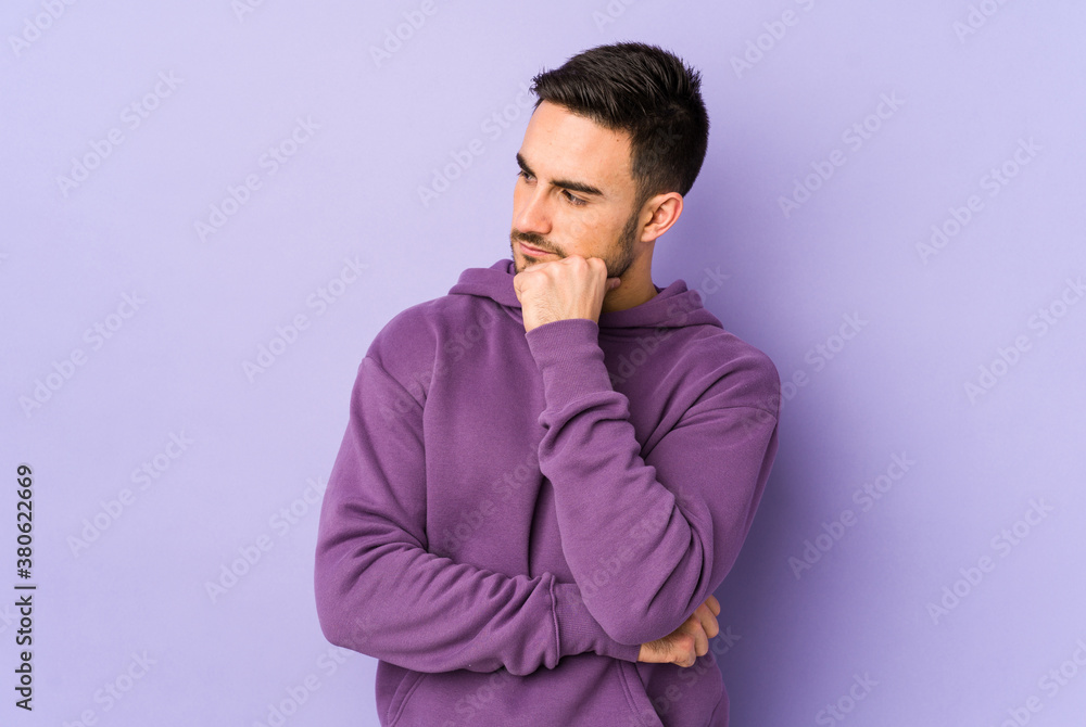 Young caucasian man isolated on purple background looking sideways with doubtful and skeptical expression. Young caucasian man isolated on purple background looking sideways with doubtful and skeptical expression.