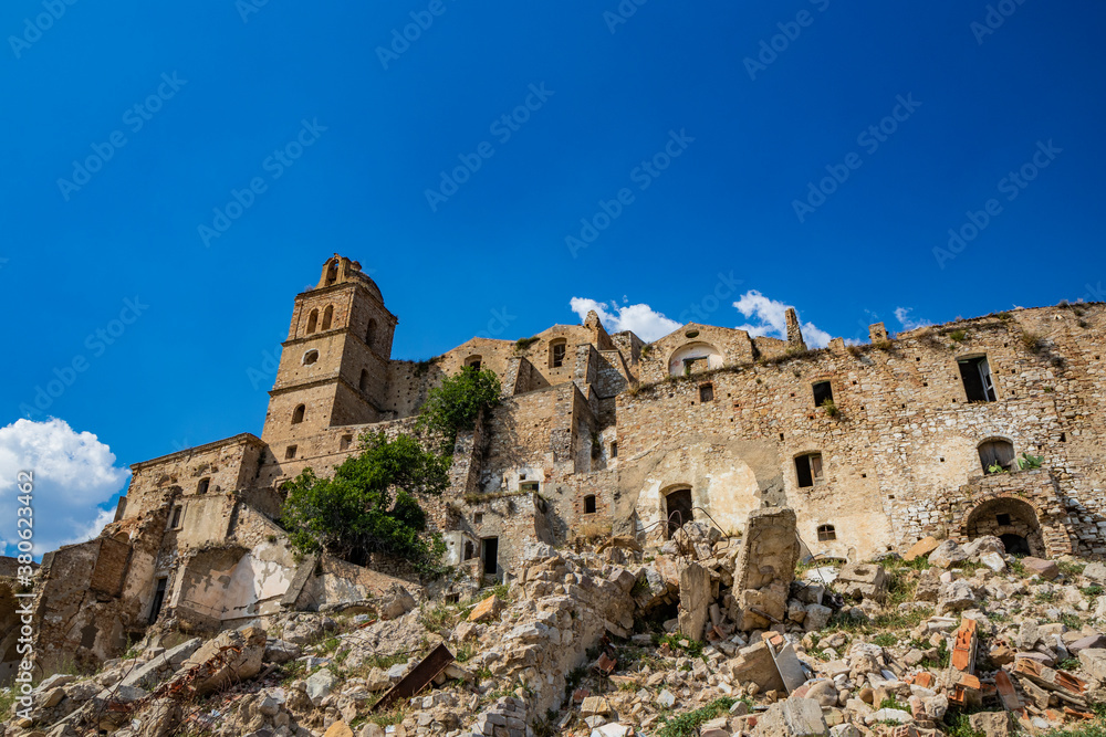 Craco, Basilicata, Italy. Ghost town destroyed and abandoned following a landslide. Collapsed houses and the remains invaded by vegetation. Broken walls, windows and doors. Bell tower of the church