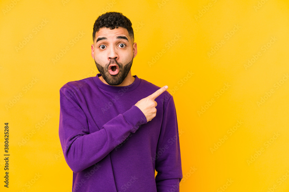 Young mixed race arabic man isolated pointing to the side Young mixed race arabic man isolated pointing to the side