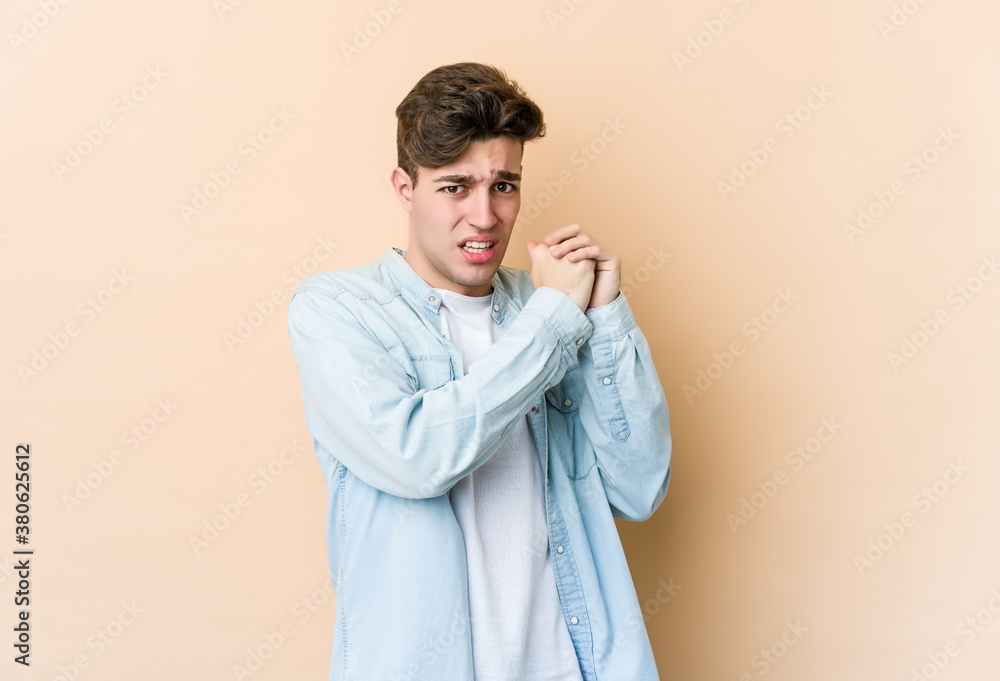 Young caucasian man isolated on beige background scared and afraid. Young caucasian man isolated on beige background scared and afraid.