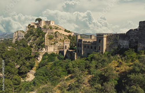 Aerial image picturesque view to ancient famous castle of Xativa against cloudy sky background. Spanish landmark located on hillside top green mountain surrounding countryside. Valencia  Spain
