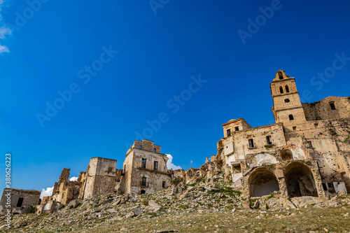 Craco, Basilicata, Italy. Ghost town destroyed and abandoned following a landslide. Collapsed houses and the remains invaded by vegetation. Broken walls, windows and doors. Bell tower of the church