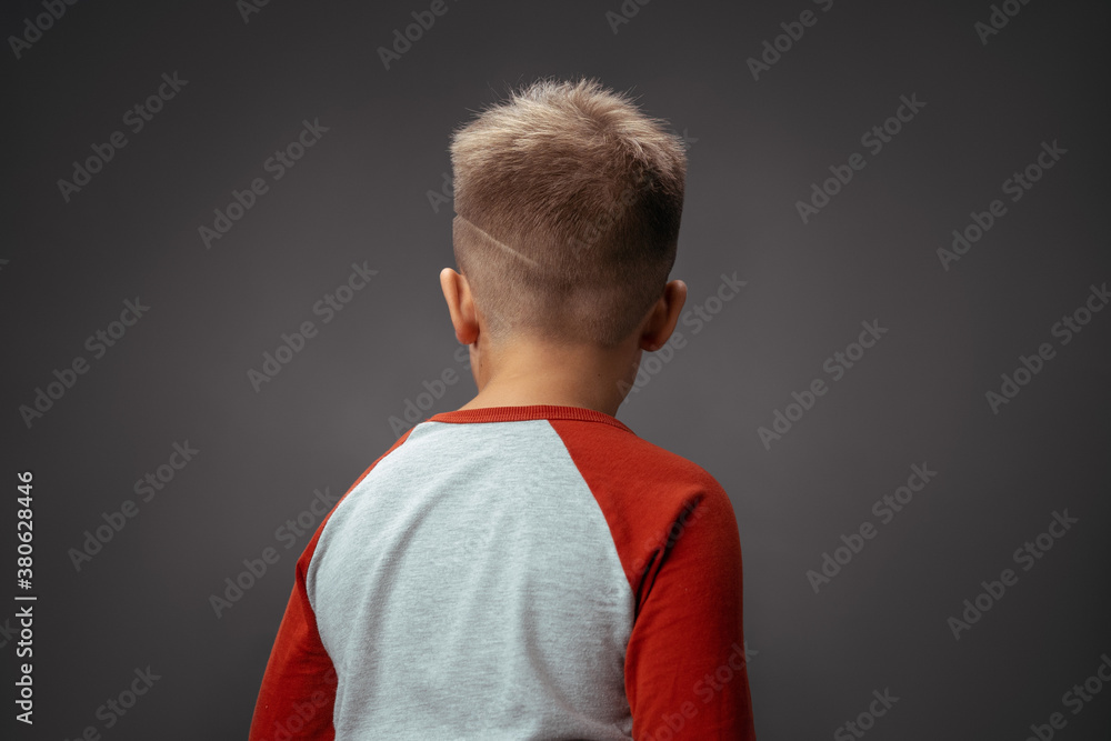 Child turned his back to the camera. Children's drama concept. Boy offended by isolated background. High quality photo. Child turned his back to the camera. Children's drama concept. Boy offended by isolated background. High quality photo.