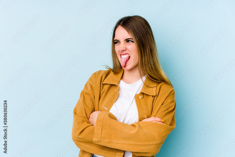 Young caucasian woman isolated on blue background funny and friendly sticking out tongue. Young caucasian woman isolated on blue background funny and friendly sticking out tongue.