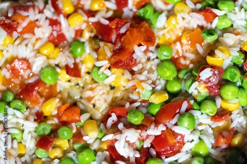 Hawaiian rice with peppers green peas corn. cooked in a frying pan background.